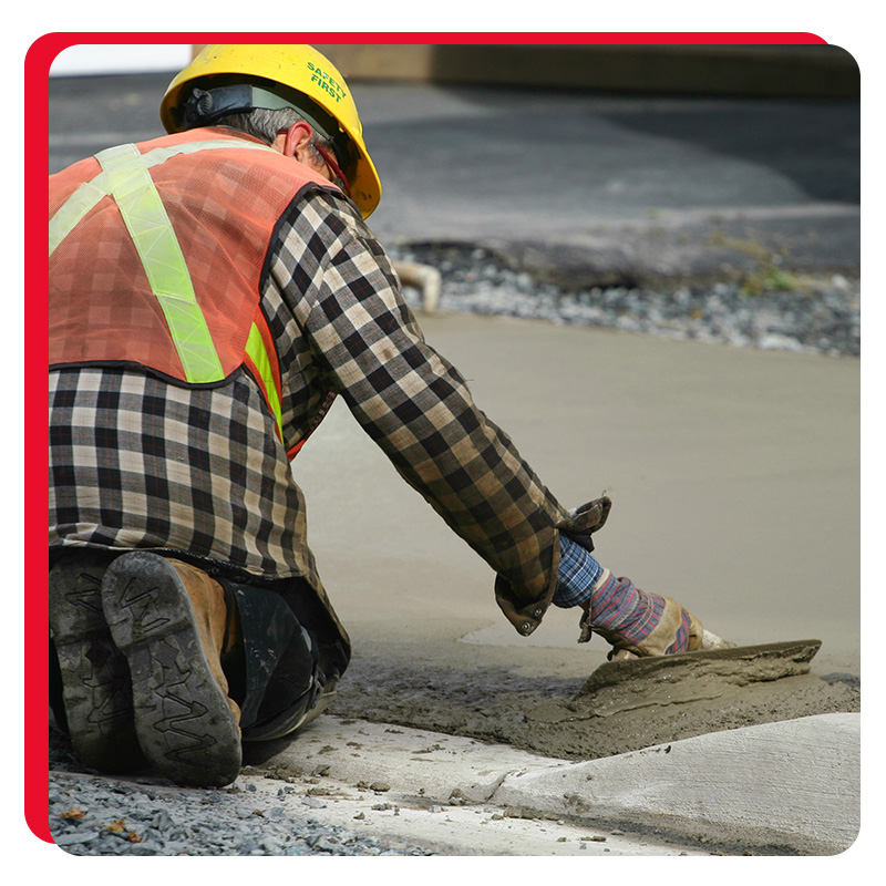 A construction worker paving the sidewalk with concrete